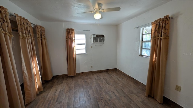 unfurnished room with dark hardwood / wood-style floors, an AC wall unit, ceiling fan, and a healthy amount of sunlight