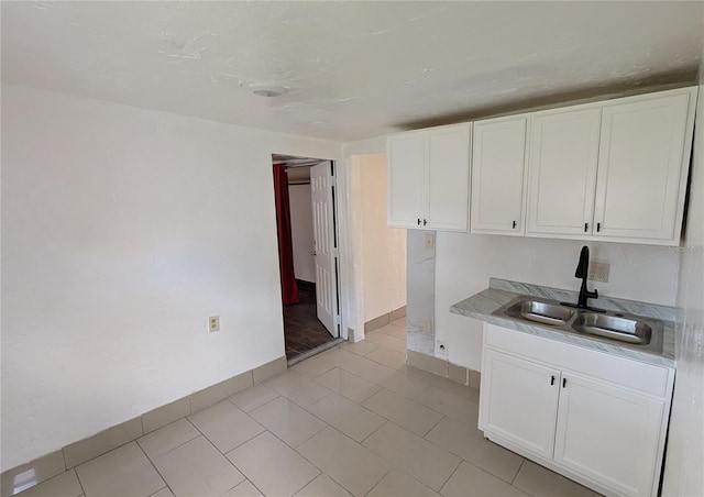 kitchen featuring white cabinetry, sink, and light tile patterned flooring