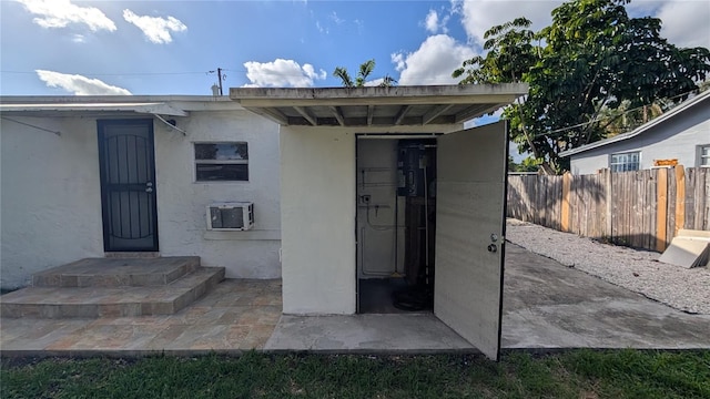 entrance to property featuring an AC wall unit and a patio area