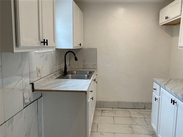 kitchen with white cabinets, decorative backsplash, and sink