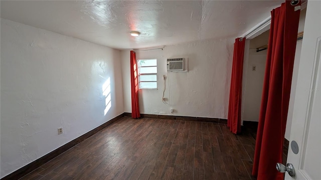 spare room with an AC wall unit and dark wood-type flooring