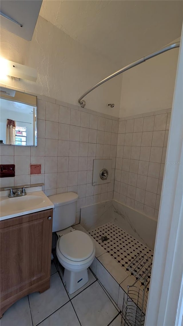 bathroom featuring a tile shower, vanity, tile walls, and toilet