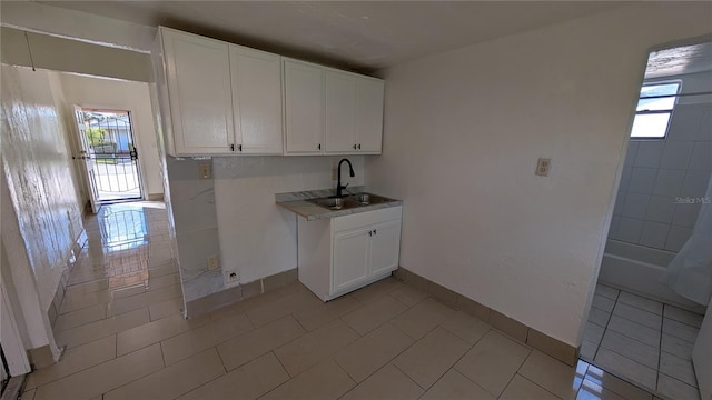 clothes washing area with a healthy amount of sunlight, light tile patterned floors, and sink