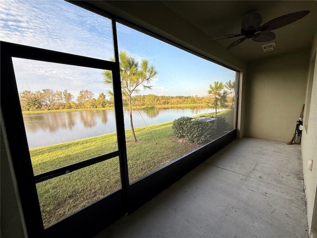 unfurnished sunroom featuring ceiling fan and a water view