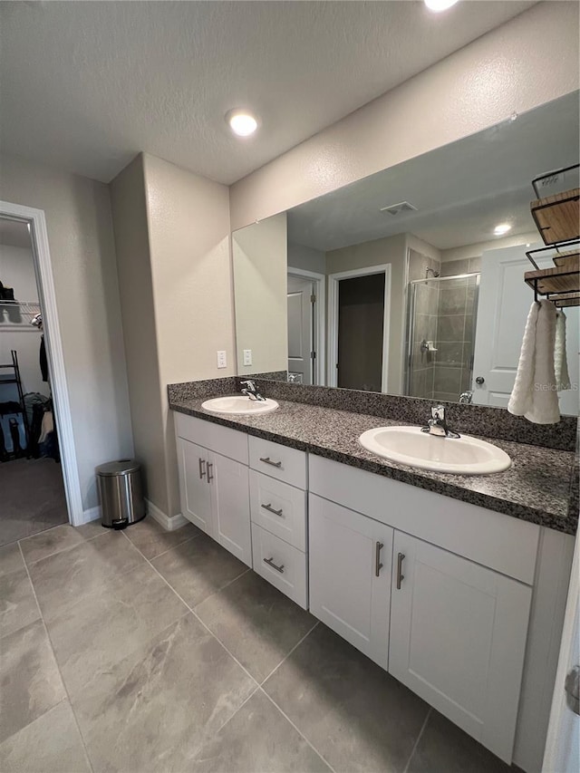 bathroom featuring tile patterned flooring, vanity, a shower with door, and a textured ceiling