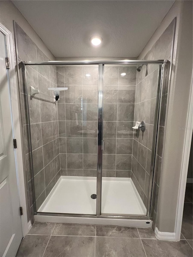 bathroom with tile patterned floors, a textured ceiling, and walk in shower