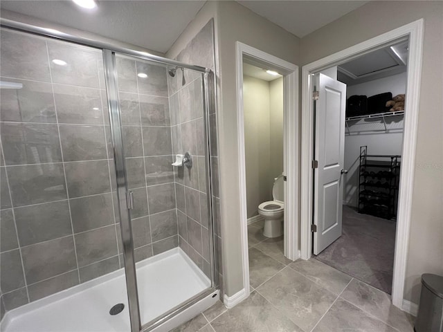 bathroom featuring tile patterned flooring, toilet, and a shower with shower door