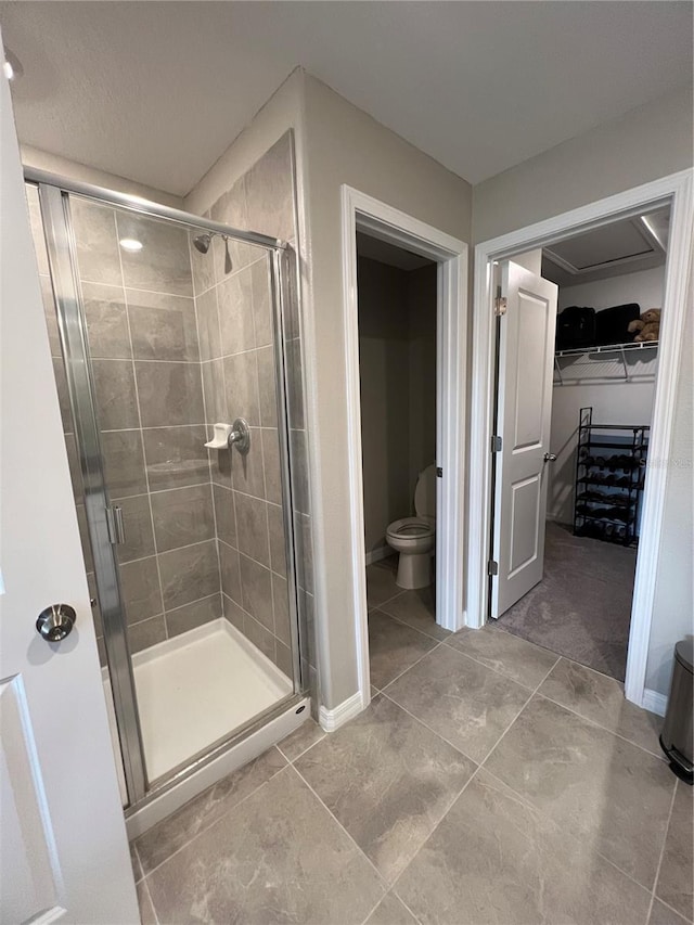 bathroom featuring tile patterned floors, toilet, and walk in shower