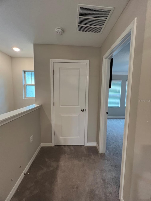 corridor with dark carpet and a wealth of natural light