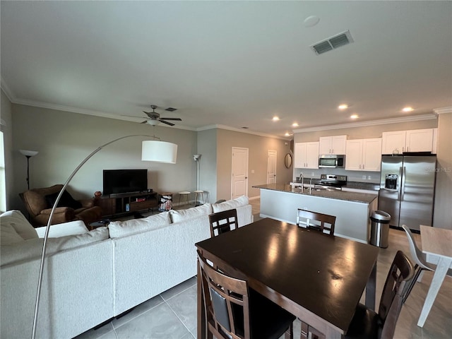 tiled dining area with crown molding, sink, and ceiling fan