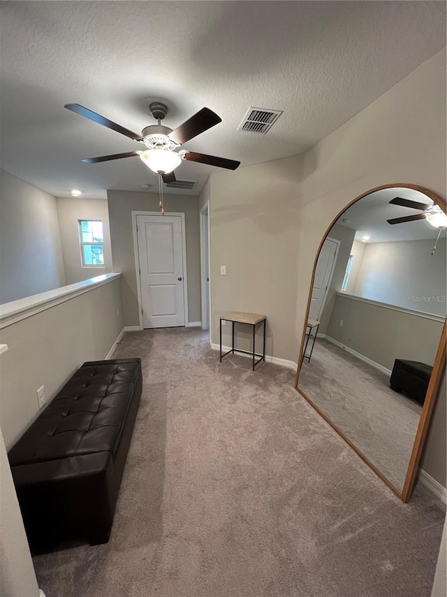 sitting room with carpet flooring, ceiling fan, and a textured ceiling