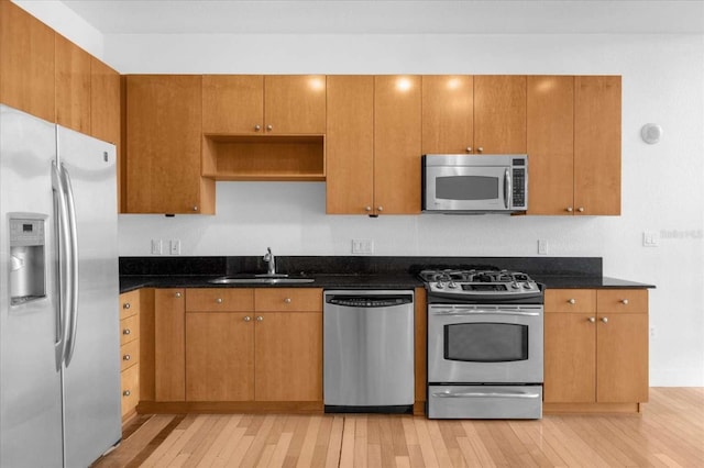 kitchen with light hardwood / wood-style floors, sink, stainless steel appliances, and dark stone counters