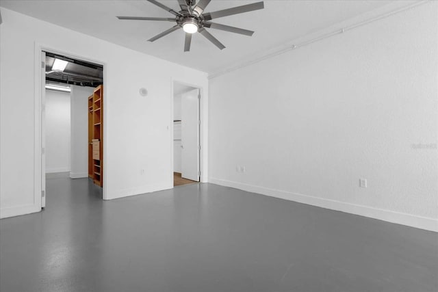 unfurnished bedroom with a walk in closet, concrete floors, a closet, and ceiling fan