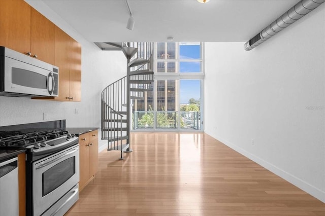 kitchen featuring stainless steel appliances, dark countertops, light wood-style floors, baseboards, and expansive windows