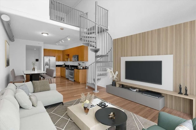 living area with stairs, light wood-style floors, wallpapered walls, and an accent wall