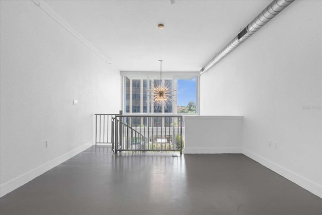 unfurnished room featuring concrete flooring, a chandelier, baseboards, and floor to ceiling windows