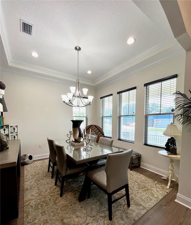 dining space with a notable chandelier, crown molding, a textured ceiling, and hardwood / wood-style flooring