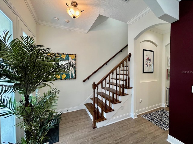 entrance foyer with crown molding, wood-type flooring, and a textured ceiling