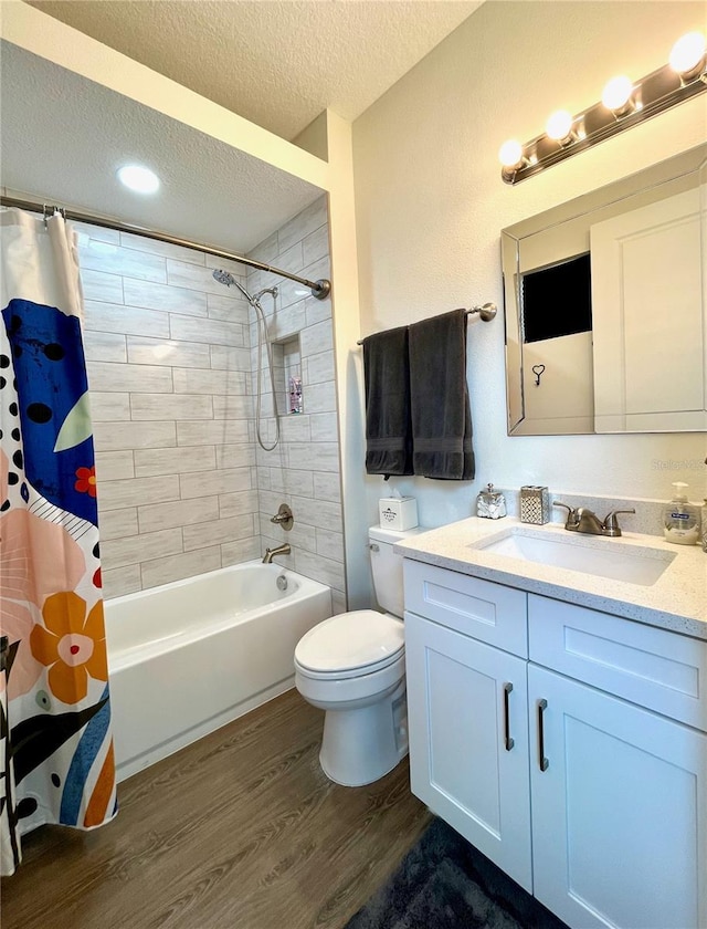 full bathroom with hardwood / wood-style floors, vanity, shower / bath combination with curtain, toilet, and a textured ceiling