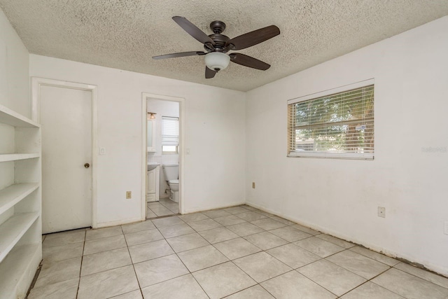 tiled spare room featuring a wealth of natural light, ceiling fan, and a textured ceiling