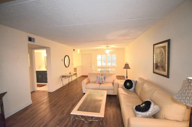 living room with ceiling fan, dark wood-type flooring, and a textured ceiling