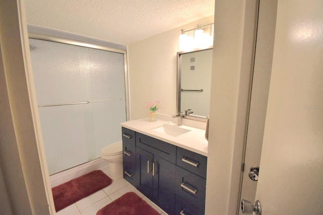 bathroom featuring vanity, a textured ceiling, a shower with door, tile patterned flooring, and toilet