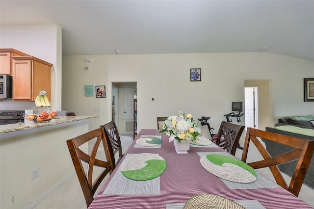 dining area featuring light carpet and vaulted ceiling