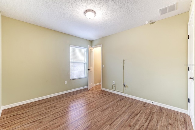 unfurnished room featuring light hardwood / wood-style floors and a textured ceiling