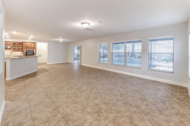 unfurnished living room with light tile patterned floors and a textured ceiling