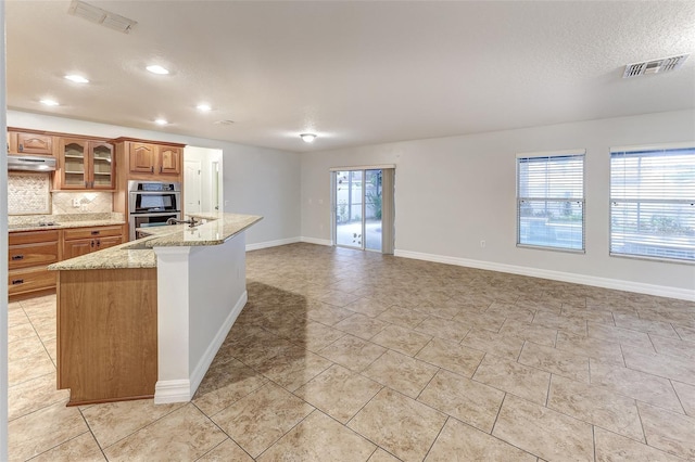 kitchen with a wealth of natural light, decorative backsplash, sink, and stainless steel double oven