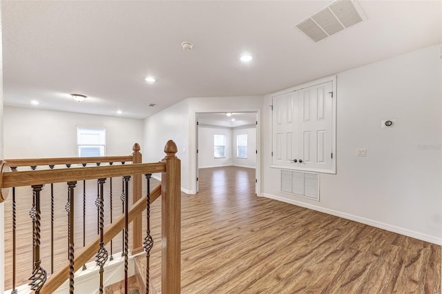 corridor with a wealth of natural light and hardwood / wood-style flooring