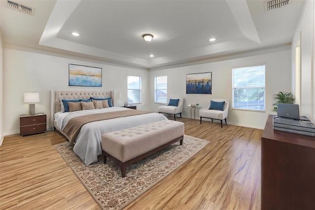 bedroom featuring a tray ceiling and light hardwood / wood-style flooring