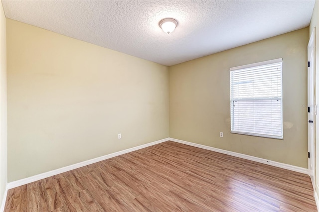 unfurnished room featuring light wood-type flooring and a textured ceiling