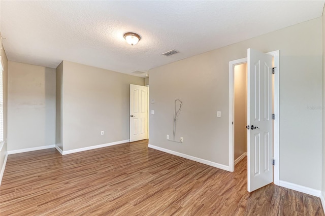 empty room featuring a textured ceiling and light hardwood / wood-style floors