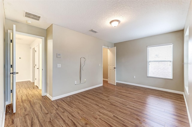 unfurnished room featuring wood-type flooring and a textured ceiling