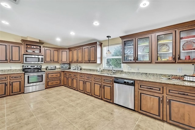 kitchen with sink, hanging light fixtures, light tile patterned floors, light stone countertops, and appliances with stainless steel finishes