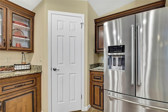 kitchen featuring light stone countertops, stainless steel fridge, and vaulted ceiling