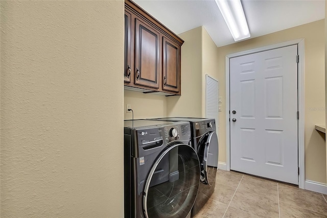 laundry area with light tile patterned flooring, cabinets, and independent washer and dryer