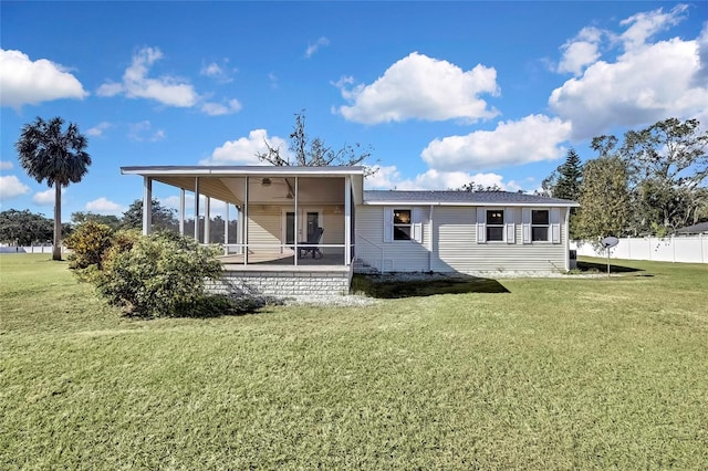 rear view of property featuring a sunroom, ceiling fan, and a yard