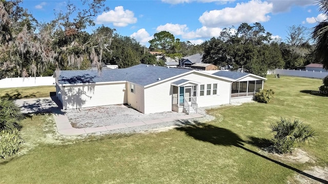 rear view of house featuring a lawn and a sunroom