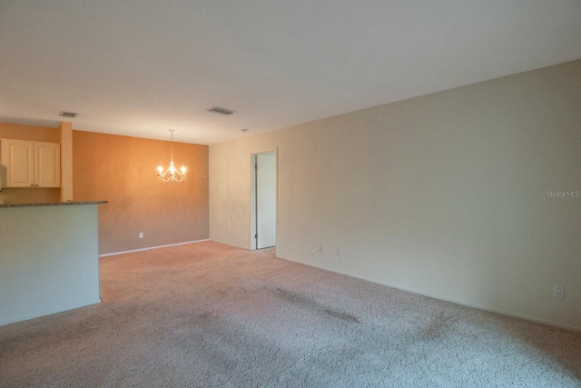 spare room with light carpet and a chandelier