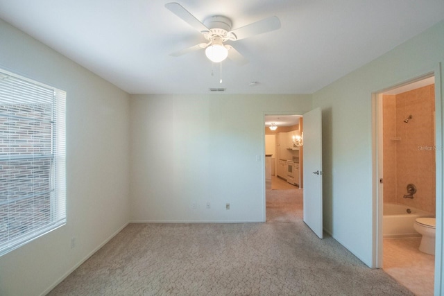 unfurnished bedroom with connected bathroom, light colored carpet, and ceiling fan