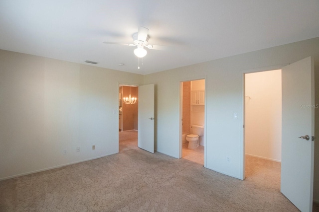 unfurnished bedroom featuring ceiling fan, a walk in closet, light carpet, and connected bathroom