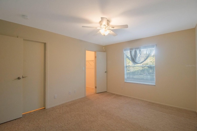 unfurnished bedroom with ceiling fan, a closet, carpet, and a spacious closet