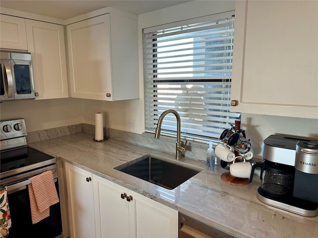 kitchen featuring white cabinetry, sink, light stone countertops, and appliances with stainless steel finishes