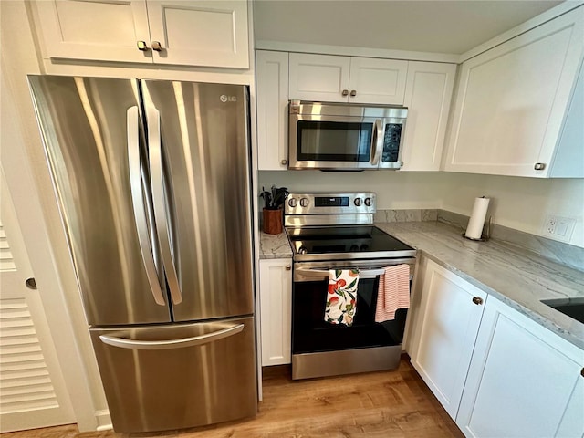 kitchen featuring white cabinetry, stainless steel appliances, light stone counters, and light hardwood / wood-style floors