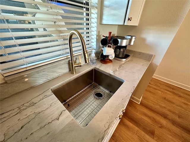 details featuring light wood-type flooring, white cabinetry, and sink