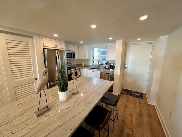 kitchen with white cabinetry, sink, light wood-type flooring, and appliances with stainless steel finishes