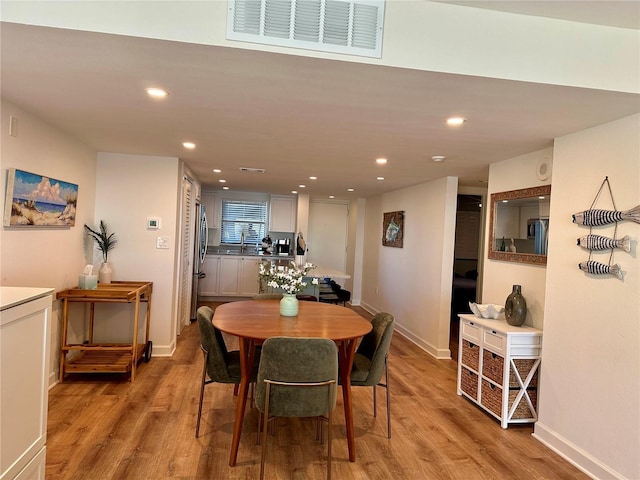 dining space with sink and light hardwood / wood-style flooring