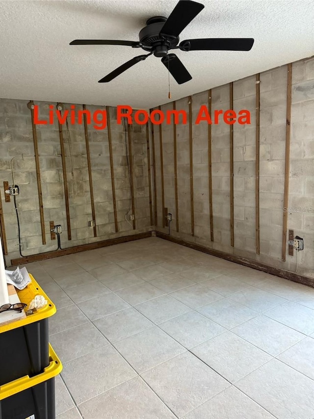 basement with ceiling fan and a textured ceiling